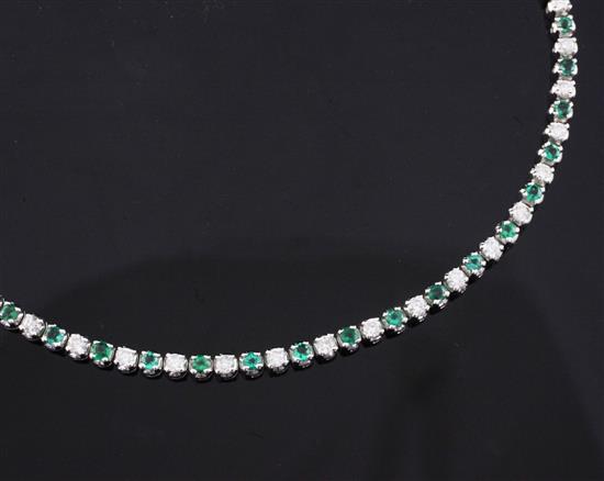 An 18ct white gold, emerald and diamond line bracelet, 7in.